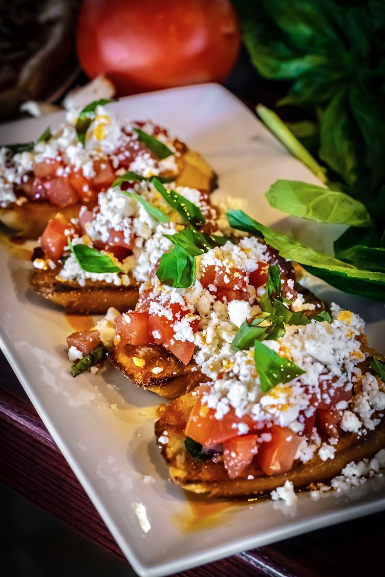Bruschetta topped with tomato, feta, and basil